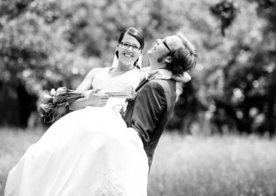 Brautpaar lacht glücklich, Bräutigam hebt Braut hoch. Hochzeitsfoto im Hofgarten Schloss Dachau.