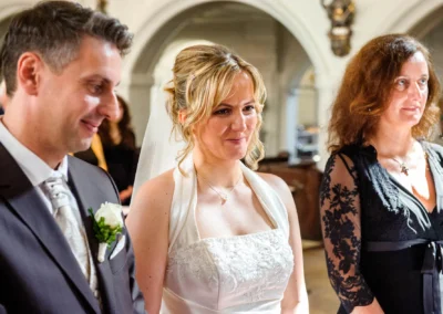 Brautpaar bei kirchlicher Trauung in Sankt Sylvester Muenchen, umgeben von Gaesten, festlich gekleidet.