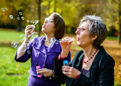 Zwei Frauen pusten Seifenblasen im englischen Garten Muenchen bei einer Hochzeitsreportage im Herbstwetter.