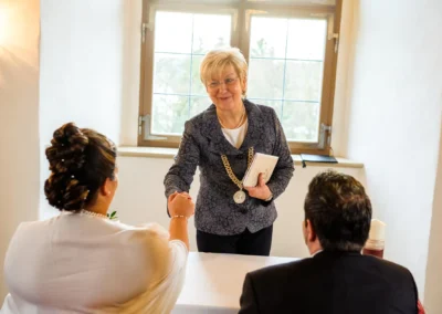 Standesamtliche Trauung bei Hochzeit im Schloss Hochstädt, Brautpaar mit Standesbeamtin während der Zeremonie.