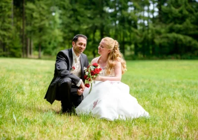Brautpaarfoto bei der Hochzeit im Gruenen, lachend mit Blumenstrauss, im Dachauer Hinterland. Hochzeitsfotografie.