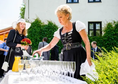 Frau schenkt Sekt bei einer Hochzeit im Freien ein, Gasthof zur Muehle Ismaning, nördlich von Muenchen.