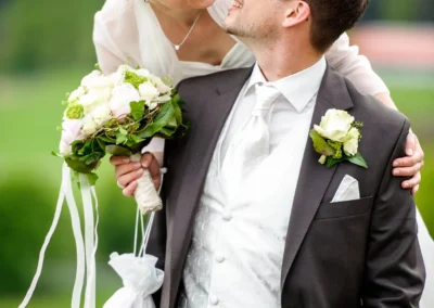 Brautpaar beim Fotoshooting im Aschbacher Hof, sie lacht, er haelt Blumen, Hochzeitsreportage Südlich München.