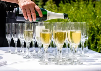 Champagner wird in Gläser bei einer Hochzeit im Gasthof zur Mühle Ismaning serviert. Hochzeitsfoto in elegantem Stil.