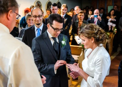 Braut und Braeutigam tauschen Ringe in Kirche, Hochzeitsfotografie in Harkirchen, Gaeste im Hintergrund.