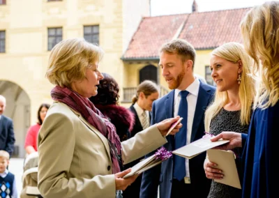 Gäste tauschen Karten bei Hochzeit auf Burg Trausnitz aus. Elegante Kleidung bei sonnigem Wetter. Hochzeitsreportage.