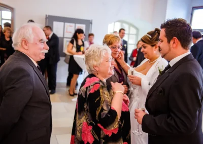 Gesellschaft bei Hochzeit im Schloss Hochstadt an der Donau, Braut und Gaeste lachen und unterhalten sich. Hochzeitsfotografie.