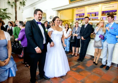 Brautpaar beim Empfang im Palmenhaus Schloss Nymphenburg umringt von Hochzeitsgaesten. Hochzeitsreportage Munich.
