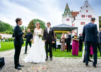 Brautpaar und Gäste bei einer Hochzeitsfeier im Schloss Gruenau, lebendige Hochzeitsreportage mit weißem Kleid.