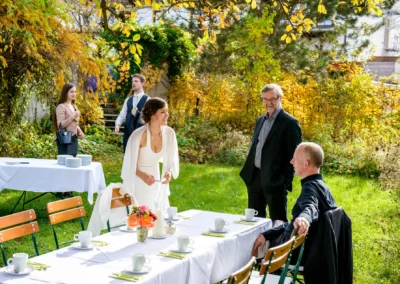 Braut im Garten bei Hochzeitsfest mit Gaesten, Tisch mit Tee, aufgenommen in alter wirt gruenwald. Hochzeitsfoto.