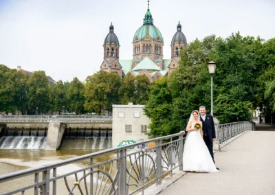 Brautpaar auf einer Bruecke vor Kirche in Muenchen-Lehel, Hochzeitsfoto bei der Hochzeitsreportage nahe Isar.
