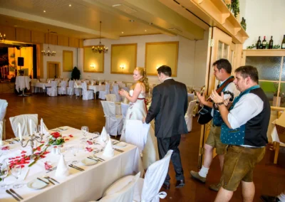 Brautpaar betritt den festlich dekorierten Saal beim Landgasthof Brummer, begleitet von Musikern. Hochzeitsfotografie.