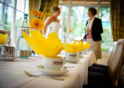 Hochzeitsfoto in Miesbach: Tischdekoration mit gelben Servietten, Teetassen und Blumenarrangement, Aufnahme bei der Hochzeit.