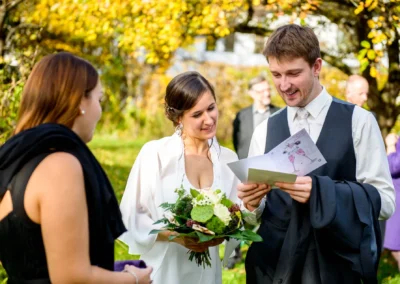 Brautpaar liest Glueckwunschkarte bei Hochzeit im Freien, Hochzeitsfotografien in Grunwald, bei Muenchen.