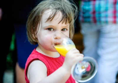 Kind trinkt Orangensaft bei einer Hochzeit in Ismaning, festgehalten von einem Hochzeitsfotografen.