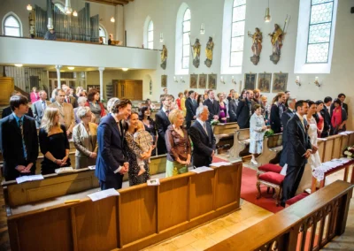 Gäste während einer kirchlichen Trauung in München Pasing. Hochzeitsreportage in einer Kirche.