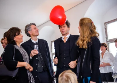 Gäste unterhalten sich bei einer Hochzeit mit rotem Herzluftballon, aufgenommen bei Schloss Höchstädt an der Donau.