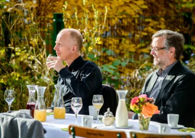 Zwei Herren an Hochzeitstisch bei alter wirt grünwald mit Saft und Blumen. Hochzeitsfotografin aus München.