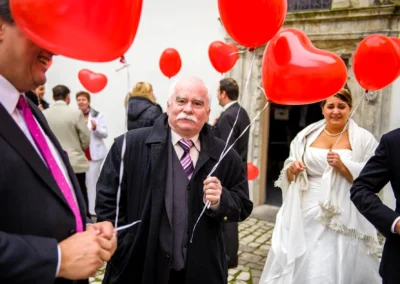 Hochzeitsreportage vor Schloss Hochstädt an der Donau. Menschen mit roten Luftballons und Braut im Hintergrund.