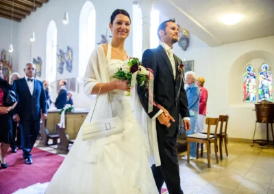 Brautpaar bei kirchlicher Trauung in München, Hochzeitsfotografie mit glücklichen Gästen in der Kirche.