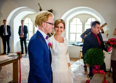 Brautpaar während der kirchlichen Trauung in Landshut, umgeben von Gästen. Hochzeitsfotograf auf Burg Trausnitz.