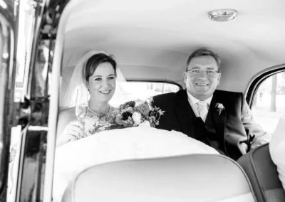 Brautpaar im Auto mit Blumenstrauss, aufgenommen bei einer Hochzeit in Muenchen-Lehel. Hochzeitsfotografien.