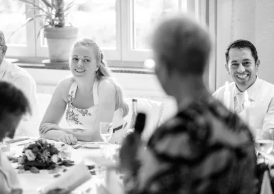 Hochzeitsreportage, laechelnde Gaeste bei einer Feier in Roermooos, festlich gedeckter Tisch mit Kerzen und Blumen.