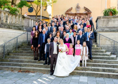 Brautpaar mit Hochzeitsgesellschaft auf Steintreppe in Schwabing, Hochzeit in Muenchen, aufgenommen bei der Hochzeitsreportage.