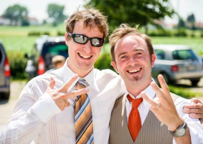 Zwei lachende Maenner bei einer Hochzeit. Aufnahme nördlich von Dachau. Hochzeitsreportage im Freien.