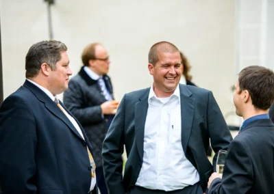 Hochzeitsgaeste in Anzug lachen bei Hochzeit im Jagdschloss Gruenau naehe Neuburg an der Donau.