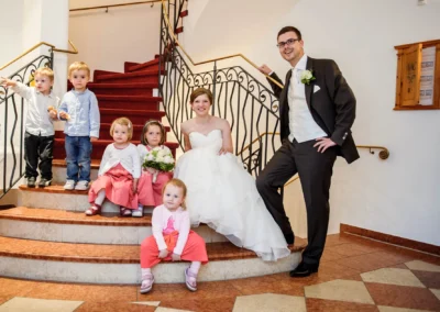 Brautpaar mit Kindern auf Treppe, Hochzeit im Aschbacher Hof, fröhliche Stimmung, Hochzeitsreportage.