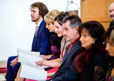 Gäste sitzen in Kirchenbank bei einer Trauung. Hochzeitsfotografie in Burg Trausnitz.