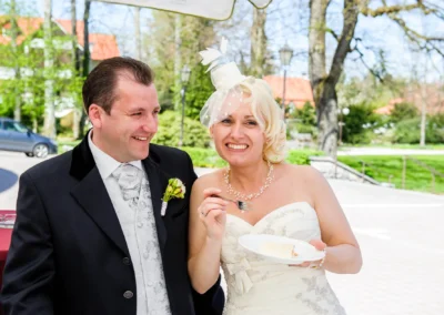 Brautpaar lacht beim Anschneiden der Hochzeitstorte bei Hochzeitsreportage in Bad Toelz im Fruehjahr.