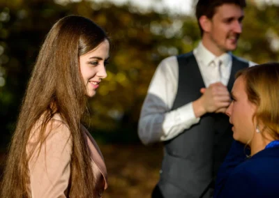 Frau lacht bei Hochzeitsreportage in Gruenwald, weitere Gaeste im Hintergrund.