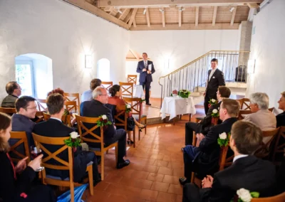 Freie Trauung in Schloss Blutenburg, Gäste sitzen auf Stühlen, Redner steht vorne, Hochzeitsreportage München.