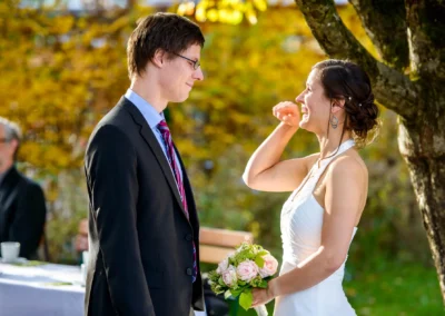 Braut und Bräutigam lächelnd im Garten beim Alten Wirt Grünwald, festlich gekleidet, bei ihrer Hochzeitsfotografie.