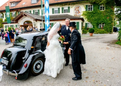 Braut steigt aus Oldtimer bei Hochzeit in Aying, aufgenommen vom Hochzeitsfotografen für eine Hochzeitsreportage.