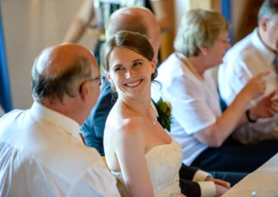 Braut lacht bei der Hochzeitsfeier in Trachtenheim Irschenberg, festgehalten in einer Hochzeitsreportage.