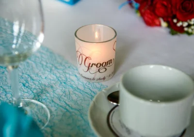 Kerze und Tasse auf Hochzeitstisch mit Blumen und Wein, Hochzeitsfoto in Orangerie Ansbach.