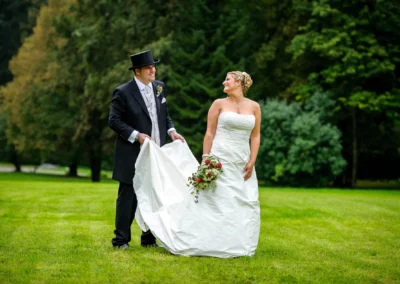 Brautpaar auf gruener Wiese, sie in weissem Kleid mit Blumenstrauss, er im Anzug in Miesbach bei Hochzeit.