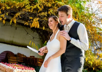 Brautpaar schneidet Torte bei Hochzeit im Garten des alten wirt grünwald, umgeben von Herbstlaub.