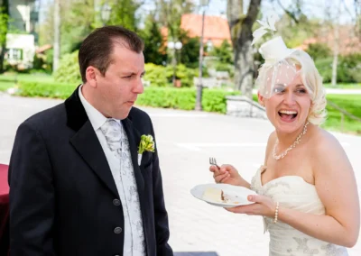 Hochzeitsfoto eines lachenden Brautpaares beim Kuchenessen im Freien, Hochzeitsreportage in Bad Toelz.