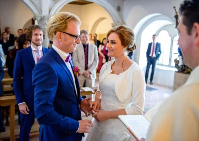 Braut und Bräutigam bei kirchlicher Trauung in Burg Trausnitz, umgeben von Gästen. Hochzeitsfotograf in Aktion.