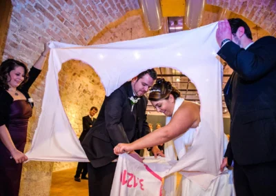 Braut und Bräutigam schneiden Herz aus Stoff bei Hochzeit in einem rustikalen Raum, nahe Dillingen. Hochzeitsfoto.
