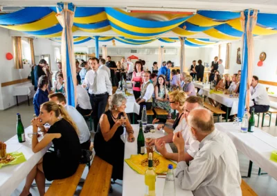 Gäste sitzen unter blau-gelbem Dekor in der Location nördlich von Dachau bei einer Hochzeitsreportage.
