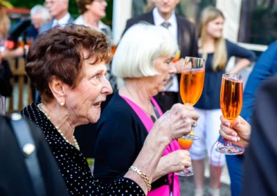 Gaste stoßen mit Sekt auf Hochzeit in Schwabing Muenchen an. Hochzeitsfotografie zeigt fröhliche Feier.