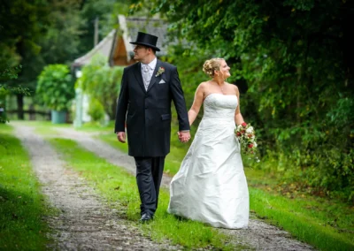 Brautpaar spaziert Hand in Hand im Gruen, Hochzeit in Miesbach, romantisches Hochzeitsfoto in idyllischer Naturumgebung.