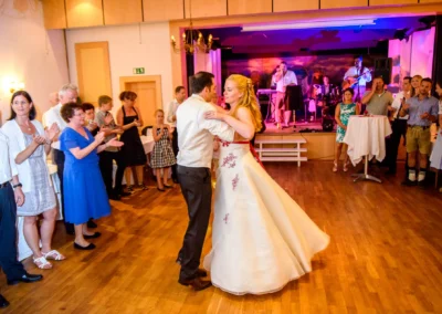 Brautpaar tanzt auf Hochzeit in Roehrmoos, Gaeste klatschen im Hintergrund, Hochzeitsreportage zeigt lebendige Szene