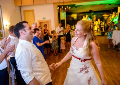 Brautpaar tanzt bei einer Hochzeit in Röhrmoos, umgeben von applaudierenden Gästen vor einer Band und Bühne.