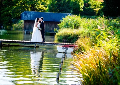 Brautpaar steht auf einem Steg am Wesslinger See und küsst sich. Hochzeitsfotografie im Freien in der Natur.
